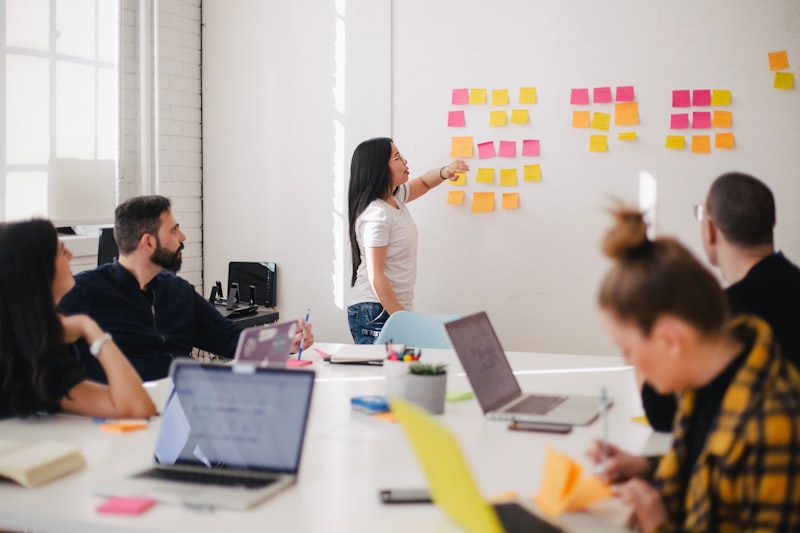 A designer adding sticky notes to a wall during a team workshop